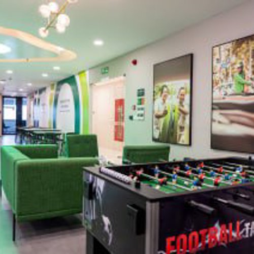 a room with a foosball table and green couches