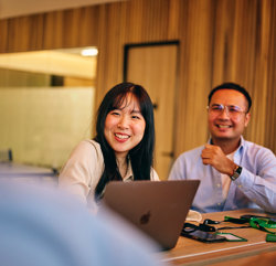 a man and woman sitting at a table with a laptop