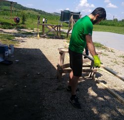 a man in green shirt and black shorts working on a wood piece