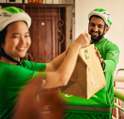 a man and woman wearing helmets and holding a brown bag