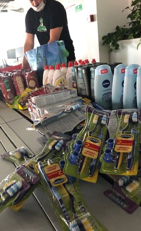 a person standing behind a counter with a variety of toothbrushes and toothpaste
