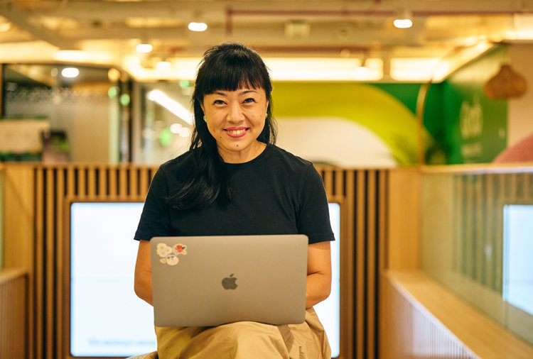 a woman sitting on a bench with a laptop