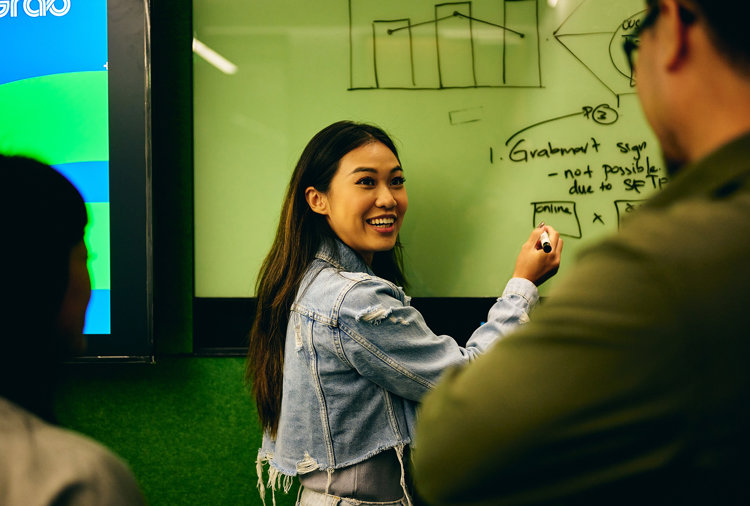 a woman writing on a whiteboard