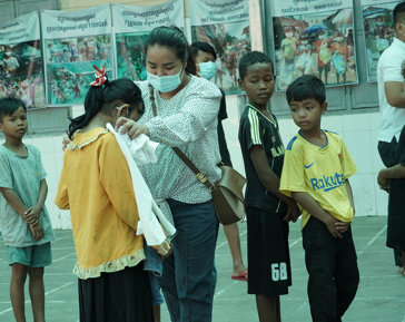a woman wearing a mask standing next to a group of children
