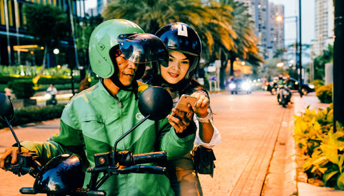 a man and woman on a scooter looking at a phone