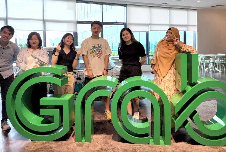 a group of people standing in front of a large green sign