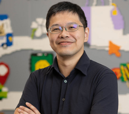a person with glasses smiling with arms crossed