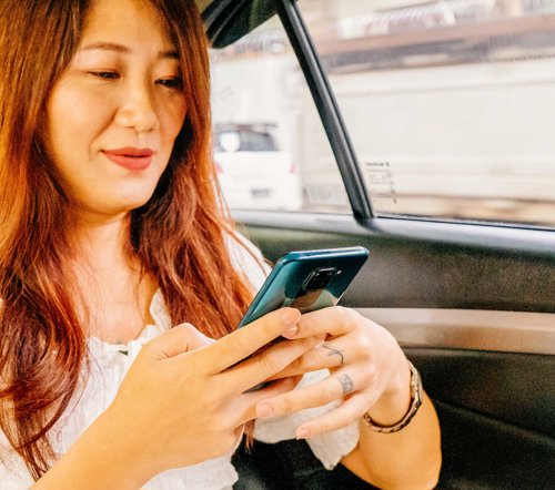 a woman sitting in a car looking at her phone