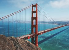 a red bridge over water with Golden Gate Bridge in the background