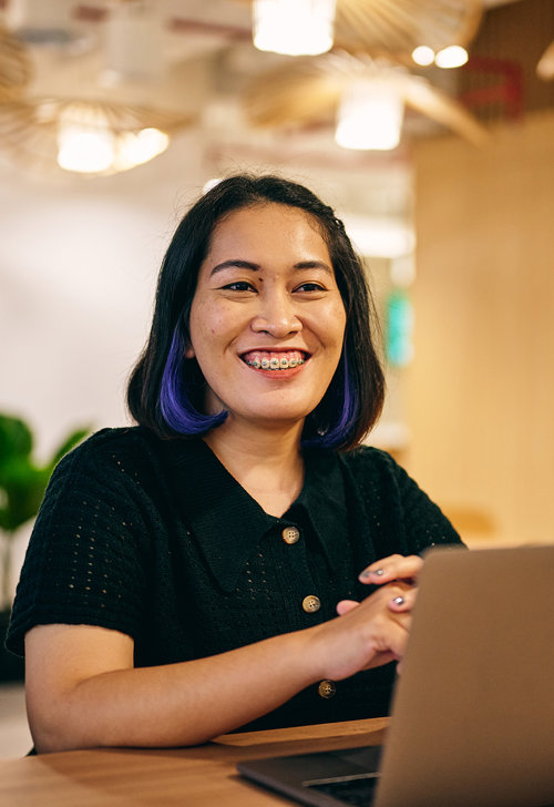 a woman smiling at a laptop