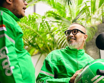 a man in green jacket with a helmet and a man in glasses