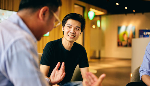 a man sitting in a chair talking to another man