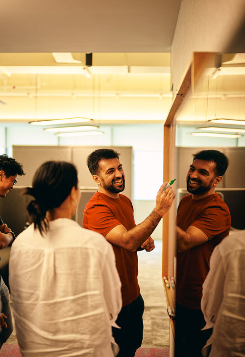 a group of people standing around a whiteboard