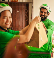 a man and woman wearing green shirts and holding a brown bag