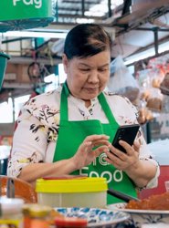 a person in a green apron holding a phone