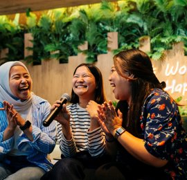 a group of women laughing and holding a microphone
