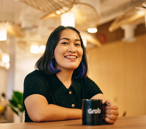 a woman sitting at a table with a mug